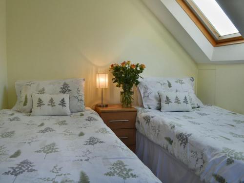 a bedroom with two beds and a vase of flowers at The Cottage in Fairlight