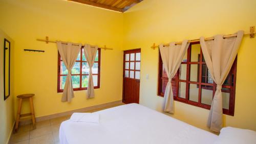 1 dormitorio con cama blanca y ventanas en La Playa Hostel, en Mazunte