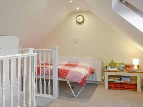 a bedroom with a crib and a clock on the wall at Sycamore Cottage in Consett