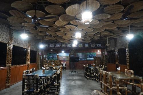 a dining room with tables and chairs and a ceiling with logs at Kaziranga Eco Camp in Hatikhuli