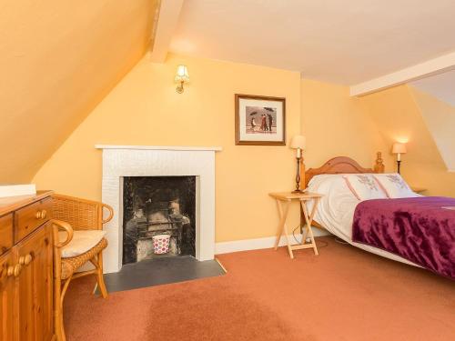 um quarto com uma cama e uma lareira em Big Barns Cottage em Backies