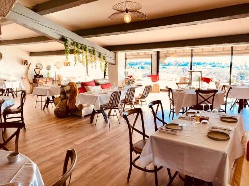 un restaurante con mesas y sillas blancas y ventanas en Château le Bouïs, en Gruissan