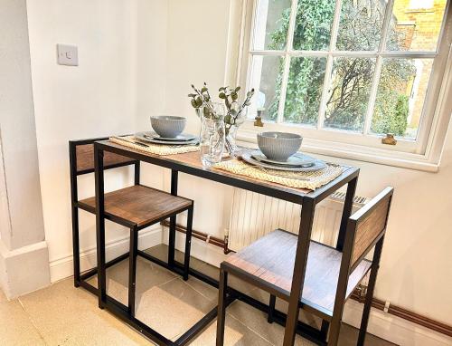 a table with two chairs and a vase of flowers at Cosy One Bedroom Apartment in Trowbridge