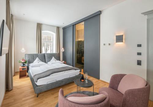 a bedroom with a bed and two chairs and a table at Villa Waldkönigin in San Valentino alla Muta
