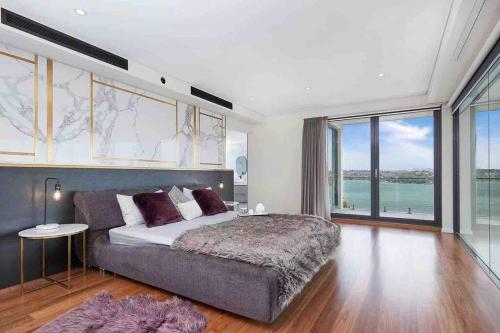 a bedroom with a large bed and a large window at SYD Luxury cheerful water view holiday house in Sydney