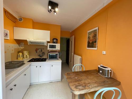 eine Küche mit orangefarbenen Wänden und einem Holztisch in der Unterkunft Appartement Cap Vern Les Bains in Capvern