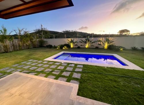 a backyard with a swimming pool and grass at Private House Buzios - casa aluguel in Búzios