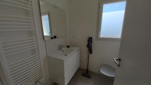 biała łazienka z umywalką i lustrem w obiekcie LES SILENES - Maison 3 chambres proche plage w mieście Saint-Jean-de-Monts