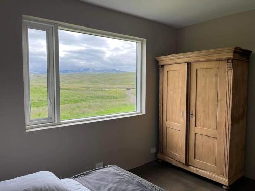 een slaapkamer met een raam, een bed en een kast bij Óspaksstaðir- New Renovated Farm in Hrútafjörður in Staður