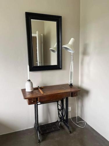 a table with a lamp and a mirror on a wall at Óspaksstaðir- New Renovated Farm in Hrútafjörður in Staður