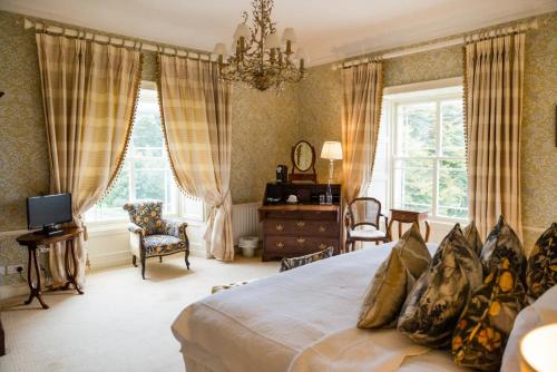 a bedroom with a bed and a chair and windows at Tankardstown House in Slane