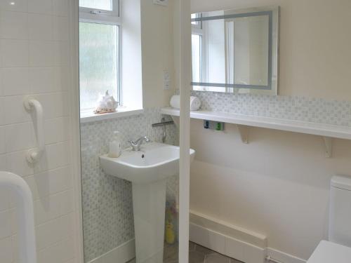 a white bathroom with a sink and a mirror at The Brambles in Horning