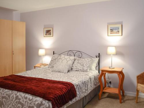 a bedroom with a bed with two lamps and two tables at Killearn Cottage in Portmahomack