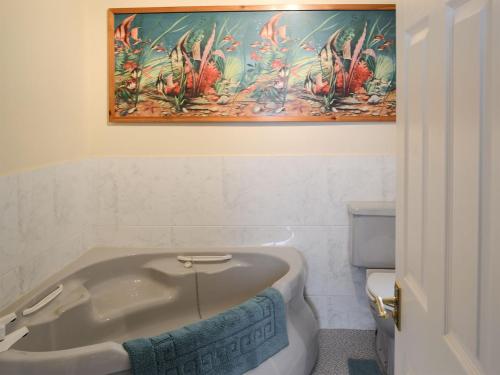 a bathroom with a bath tub and a painting on the wall at Killearn Cottage in Portmahomack