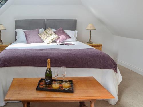 a bed with a bottle of wine and glasses on a table at Windmill Barn in Herstmonceux