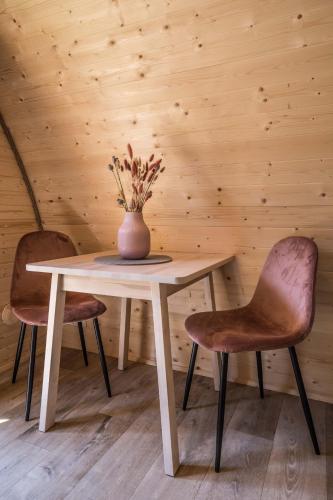 a table with two chairs and a vase with flowers on it at Luxe woodlodge in een prachtige en bosrijke omgeving in Bornerbroek