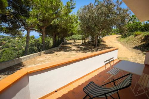 two chairs and a table on a balcony with trees at Casale la Macina Residence Scopello in Scopello