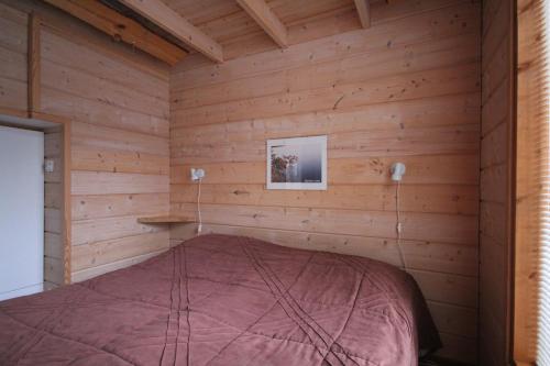 - une chambre avec un lit dans une pièce en bois dans l'établissement Haarusmaa Holiday Apartments Kauhava, à Härmä