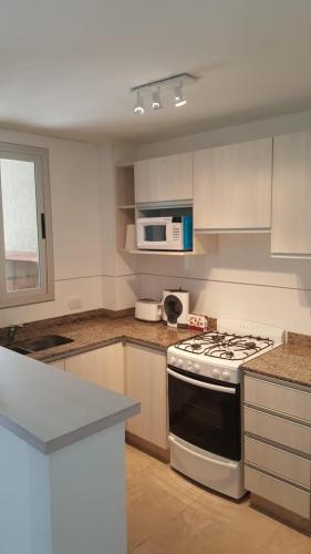 a kitchen with a stove and a microwave at Departamento Caseros in Salta
