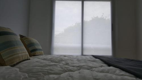 an unmade bed in front of a large window at Departamento Caseros in Salta