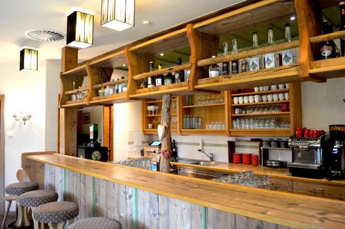 a bar in a restaurant with wooden walls and stools at Hotel zum Urviech -Erwachsenenhotel- in Ehrwald