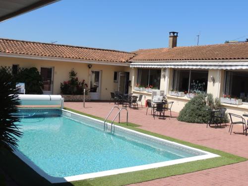 a swimming pool in front of a house at Hôtel auberge des charmilles in Sainte-Soulle