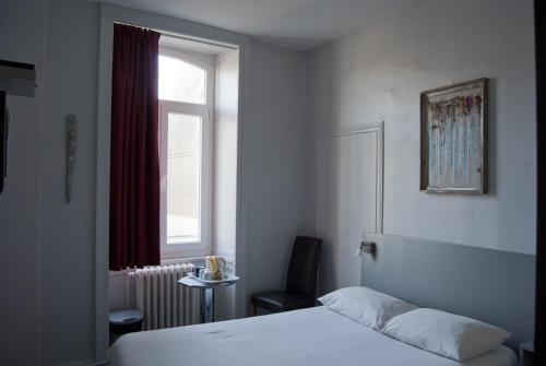 - une chambre avec un lit, une chaise et une fenêtre dans l'établissement Smartappart Cherbourg (la rose des vents), à Cherbourg en Cotentin