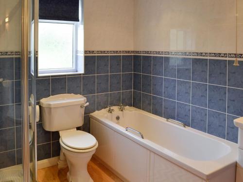 a bathroom with a toilet and a tub and a sink at Whitegate View in South Chard