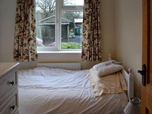 a bed in a bedroom with a window at Whitegate View in South Chard