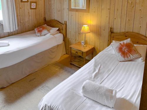 two beds in a room with wood paneled walls at The Hive in Warmwell