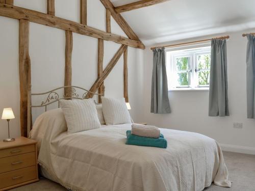 a bedroom with a large white bed with a window at The Hop Cottage in Ashperton