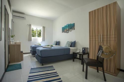 1 dormitorio con 2 camas y 1 silla en Surf Yoga Camp, en Thulusdhoo