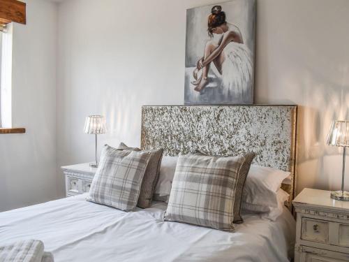 a bedroom with a white bed with a painting on the wall at The Feed Stall - UK39212 in Wimborne Minster