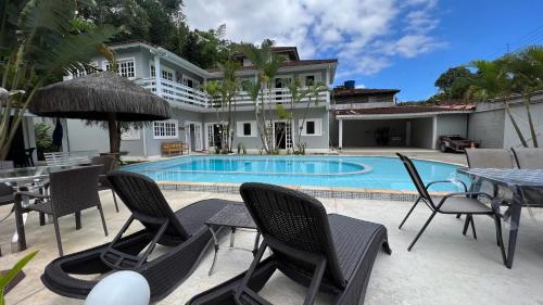 una piscina con sedie e tavolo e una casa di Linda casa na Barra do Sahy 1 (Litoral Norte SP) a São Sebastião