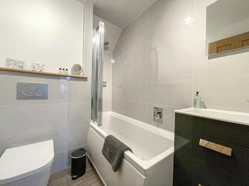 a bathroom with a tub and a toilet and a sink at Willow Cottage in Sandwick