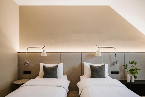 two beds in a hotel room with white sheets at Poziom 511 Jura Wellness Hotel & Spa in Ogrodzieniec