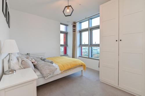 Dormitorio blanco con cama y ventanas en CannySuite en Londres