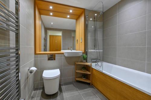y baño con aseo, lavabo y espejo. en CannySuite en Londres