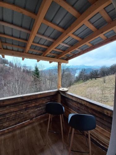 a screened in porch with two chairs and a view at Touch the Sky in Moieciu de Jos