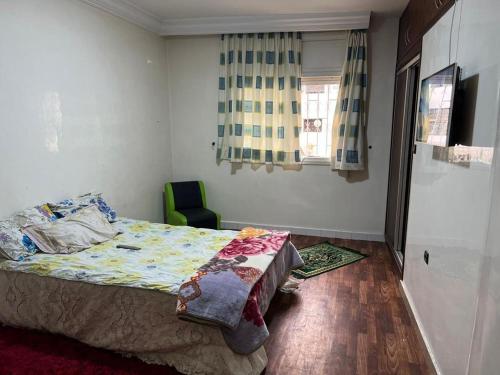 a bedroom with a bed and a green chair at Appartement calme au centre ville in Casablanca