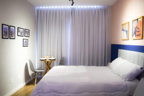 een slaapkamer met een wit bed en een tafel bij Relax Sampa in Sao Paulo