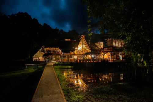 a lit up house at night with a reflection in the water at Jamu Lodge in the Cuyabeno Wildlife Reserve in Cuyavenus