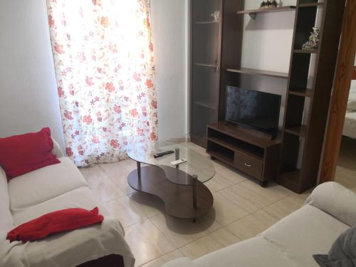 ein Wohnzimmer mit einem Couchtisch und einem TV in der Unterkunft Centro Roquetas 5 minutos de la playa en Coche Garaje solo si esta disponible in Roquetas de Mar