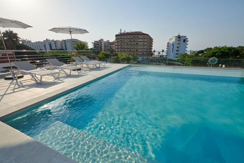 a swimming pool with chairs and umbrellas on a building at DWO Sirius - Adults Only in Santa Susanna