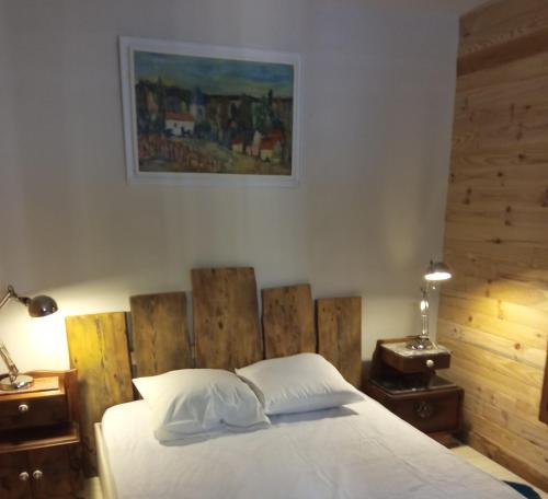 a bedroom with a white bed with a wooden headboard at Chalet papillon Domaine de la Mamounette in Boussoulet