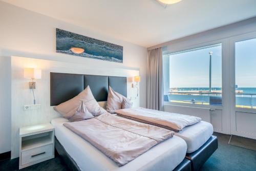 a hotel room with a bed and a large window at Hotel Hochseeinsel in Helgoland