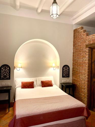 a bedroom with a large bed with an arch above it at El Rincón de las Descalzas in Carmona