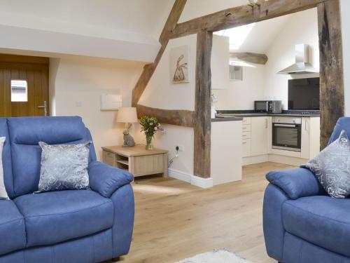 a living room with two blue chairs and a kitchen at No, 2 Ash Cottage in Quatt