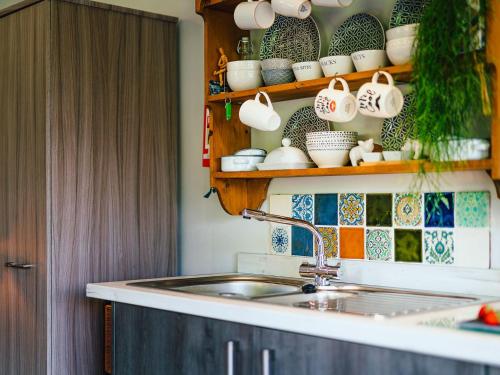 a kitchen with a sink and a shelf with dishes at Cwtch Enrico - Uk39064 in Scyborycoed