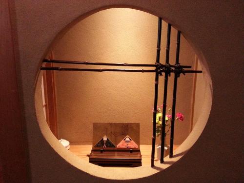 a mirror reflecting a room with a shelf and a table at Tsukimotoya Ryokan in Toyooka